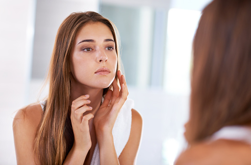 Young woman checking her face in the mirror with concerns about tooth extractionGreashaber Dentistry in Ann Arbor, MI