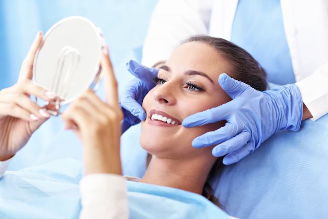 a patient looking in the mirror smiling after dental implant placement